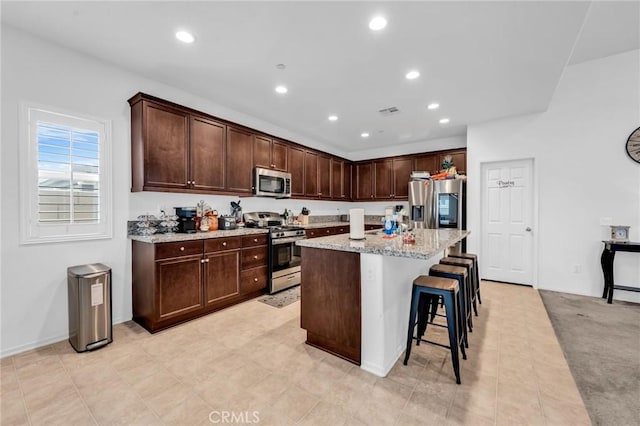 16252 Gibson St, Victorville, CA 92394 - kitchen with stainless steel appliances, dark brown cabinetry, a breakfast bar, an island with sink, and recessed lighting