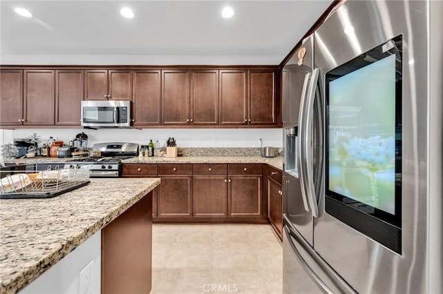 16252 Gibson St, Victorville, CA 92394 - kitchen featuring appliances with stainless steel finishes, light stone countertops, light tile patterned floors, recessed lighting, and dark brown cabinets