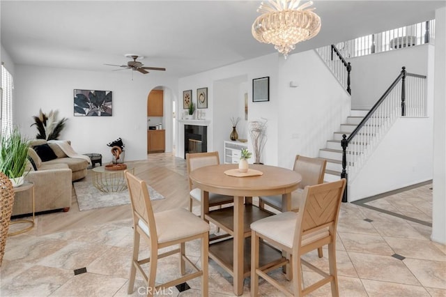 33736 Emerald Creek Ct, Temecula, CA 92592 - dining area featuring arched walkways, stairway, ceiling fan, a glass covered fireplace, and a chandelier