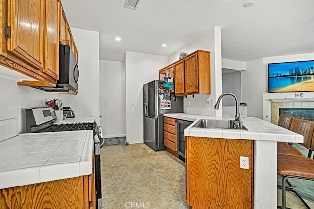 629 Ivy Crest Dr, San Jacinto, CA 92582 - kitchen featuring appliances with stainless steel finishes, tile counters, a peninsula, brown cabinetry, and recessed lighting