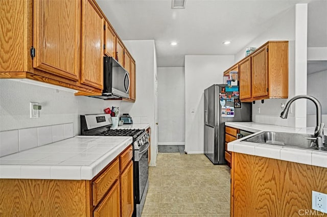 629 Ivy Crest Dr, San Jacinto, CA 92582 - kitchen with stainless steel appliances, tile counters, recessed lighting, and brown cabinetry