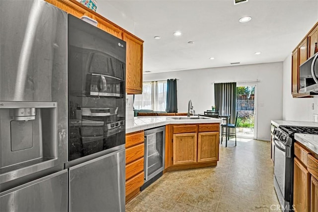 629 Ivy Crest Dr, San Jacinto, CA 92582 - kitchen with appliances with stainless steel finishes, wine cooler, a peninsula, recessed lighting, and brown cabinetry