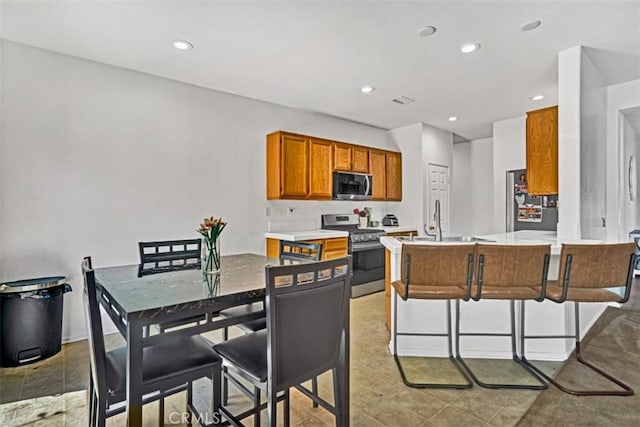 629 Ivy Crest Dr, San Jacinto, CA 92582 - kitchen featuring stainless steel range oven, a peninsula, brown cabinetry, light countertops, and recessed lighting