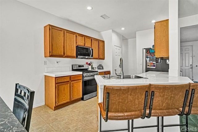 629 Ivy Crest Dr, San Jacinto, CA 92582 - kitchen featuring appliances with stainless steel finishes, a peninsula, brown cabinetry, recessed lighting, and decorative columns