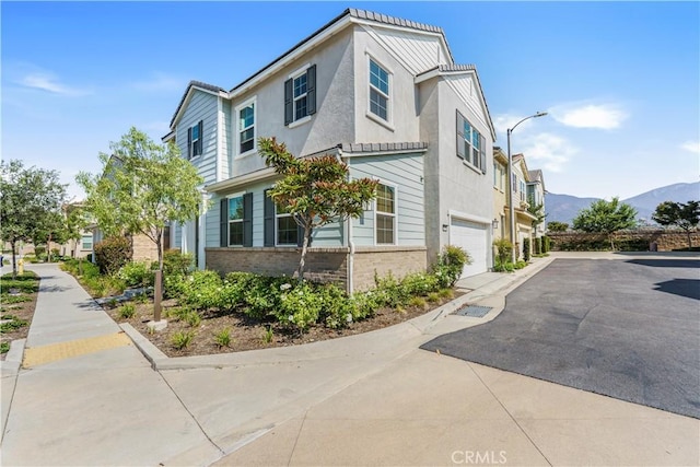 1633 Topeka Pl, Upland, CA 91784 - view of property exterior featuring an attached garage, asphalt driveway, a mountain view, brick siding, and stucco siding