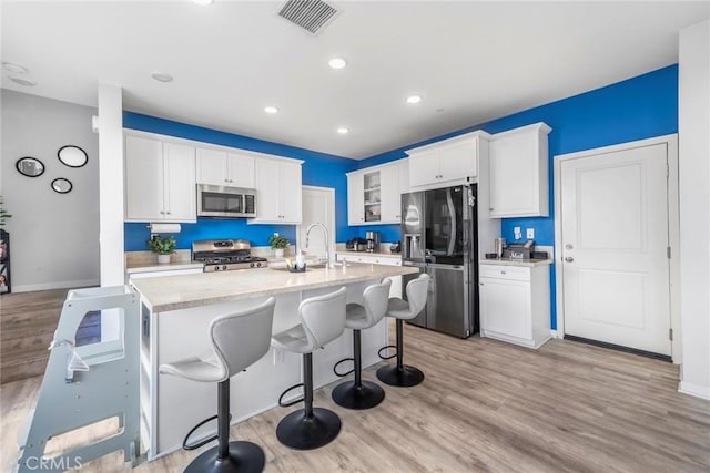 1633 Topeka Pl, Upland, CA 91784 - kitchen featuring appliances with stainless steel finishes, light wood-style flooring, a center island with sink, a kitchen breakfast bar, and recessed lighting