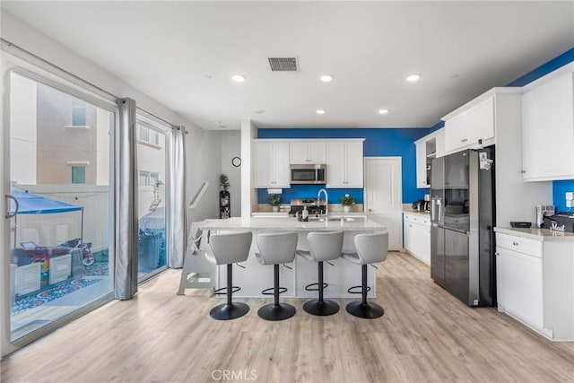 1633 Topeka Pl, Upland, CA 91784 - kitchen with appliances with stainless steel finishes, light wood-style floors, a breakfast bar area, light countertops, and recessed lighting