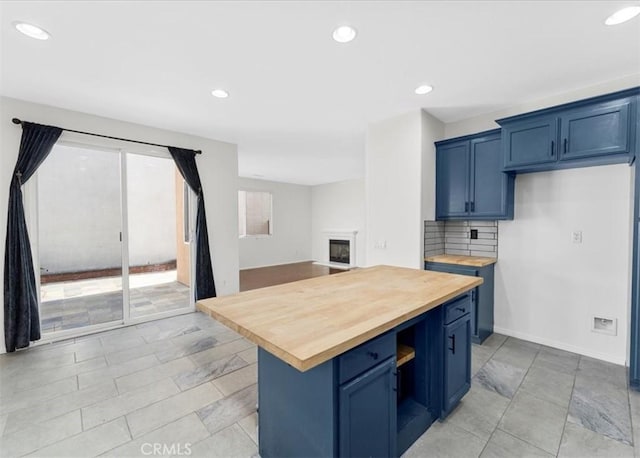 13837 Emerald Ln, Gardena, CA 90247 - kitchen featuring wooden counters, blue cabinetry, recessed lighting, decorative backsplash, and a fireplace