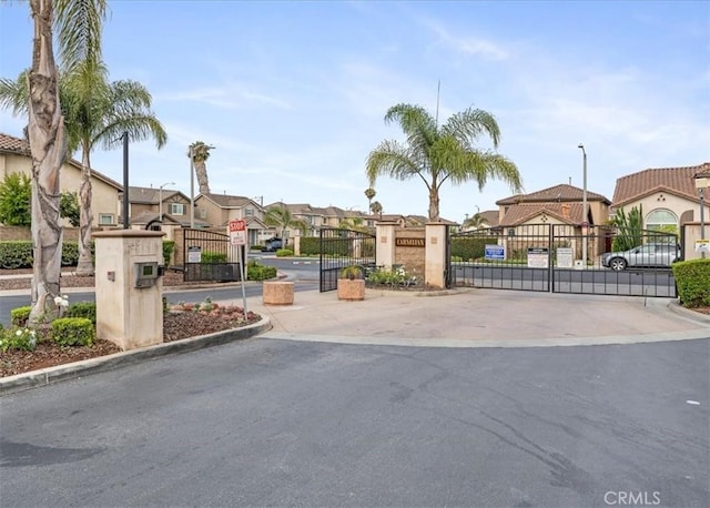13837 Emerald Ln, Gardena, CA 90247 - view of asphalt road with a residential view, a gate, street lights, a gated entry, and curbs