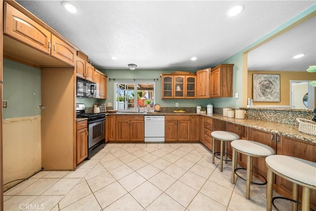 6910 Valinda Ave, Rancho Cucamonga, CA 91701 - kitchen featuring dishwasher, stainless steel gas range oven, black microwave, stone countertops, and brown cabinetry
