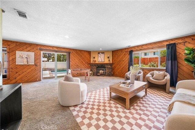 6910 Valinda Ave, Rancho Cucamonga, CA 91701 - living room featuring wooden walls, a stone fireplace, a textured ceiling, and carpet