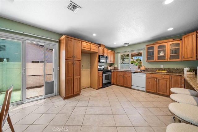 6910 Valinda Ave, Rancho Cucamonga, CA 91701 - kitchen with white dishwasher, stainless steel gas stove, black microwave, recessed lighting, and glass insert cabinets