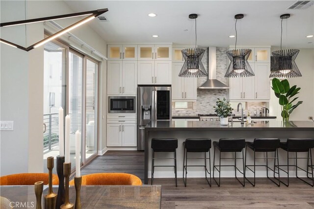 35 Ebb Tide Cir, Newport Beach, CA 92663 - kitchen featuring stainless steel refrigerator with ice dispenser, wall chimney exhaust hood, built in microwave, dark countertops, and a kitchen breakfast bar