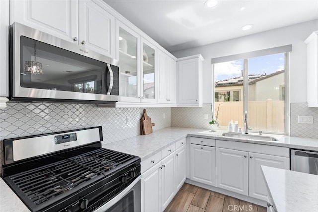 2825 Villa Catalonia Ct, Corona, CA 92881 - kitchen with appliances with stainless steel finishes, white cabinets, glass insert cabinets, backsplash, and light stone counters