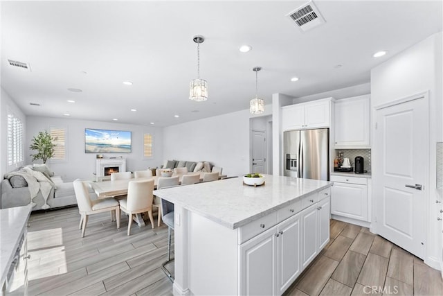 2825 Villa Catalonia Ct, Corona, CA 92881 - kitchen featuring stainless steel fridge, wood finish floors, white cabinetry, open floor plan, and a center island