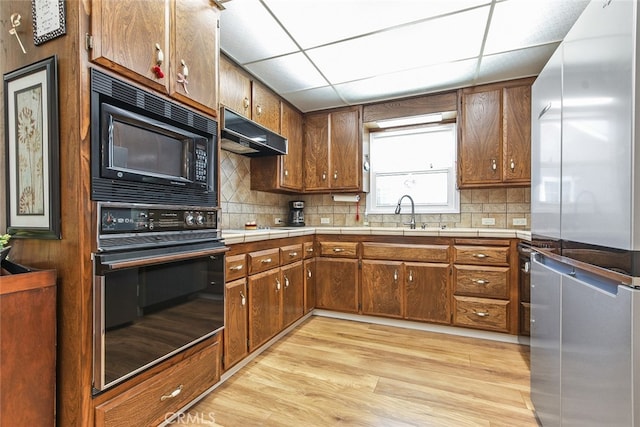 3110 N Greenbrier Rd, Long Beach, CA 90808 - kitchen featuring black appliances, under cabinet range hood, light wood-style floors, and backsplash