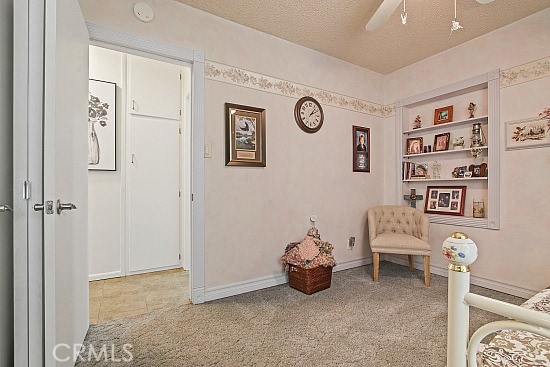 3110 N Greenbrier Rd, Long Beach, CA 90808 - living area featuring a ceiling fan, a textured ceiling, light colored carpet, and built in shelves