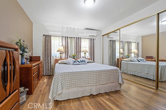 3110 N Greenbrier Rd, Long Beach, CA 90808 - bedroom with a closet, multiple windows, an AC wall unit, and wood finished floors