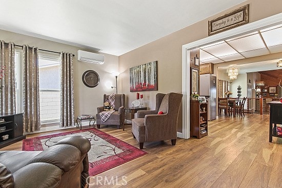 3110 N Greenbrier Rd, Long Beach, CA 90808 - living area featuring an AC wall unit and light wood-style flooring