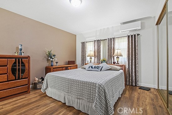 3110 N Greenbrier Rd, Long Beach, CA 90808 - bedroom with a wall unit AC, wood finished floors, and a closet