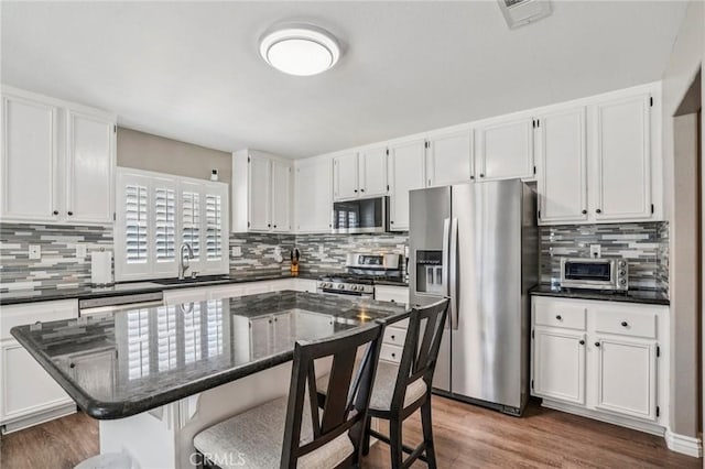 1519 Bluejay Way, Hemet, CA 92545 - kitchen with appliances with stainless steel finishes, backsplash, a kitchen breakfast bar, white cabinets, and dark wood-type flooring