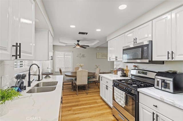 1443 E Devonshire Ave, Hemet, CA 92544 - kitchen with stainless steel microwave, range with gas stovetop, a ceiling fan, light wood-type flooring, and white cabinets