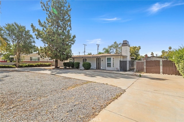 1443 E Devonshire Ave, Hemet, CA 92544 - view of front facade featuring a chimney, stucco siding, driveway, and a gate