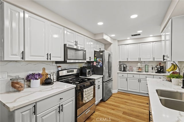 1443 E Devonshire Ave, Hemet, CA 92544 - kitchen with stainless steel appliances, white cabinetry, light wood finished floors, tasteful backsplash, and recessed lighting