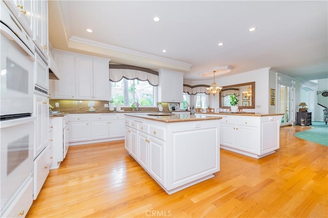 2809 Oak Knoll Dr, Diamond Bar, CA 91765 - kitchen featuring ornamental molding, a kitchen island, a chandelier, light wood-style flooring, and white cabinetry