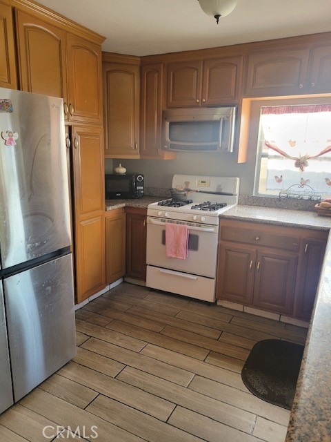 1140 W Cubbon St, Santa Ana, CA 92703 - kitchen featuring freestanding refrigerator, white gas range oven, black microwave, and light wood-style floors