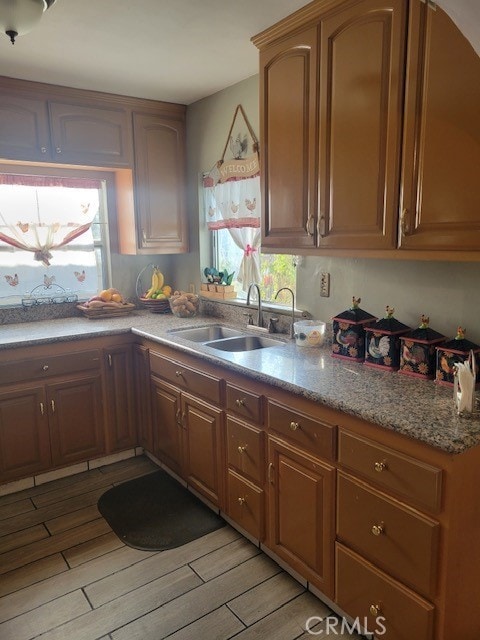 1140 W Cubbon St, Santa Ana, CA 92703 - kitchen with light wood-type flooring, light stone countertops, and brown cabinets