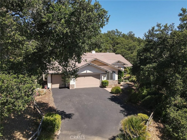 12703 Paso Verde Ct, Atascadero, CA 93422 - view of property hidden behind natural elements with asphalt driveway, an attached garage, and stone siding