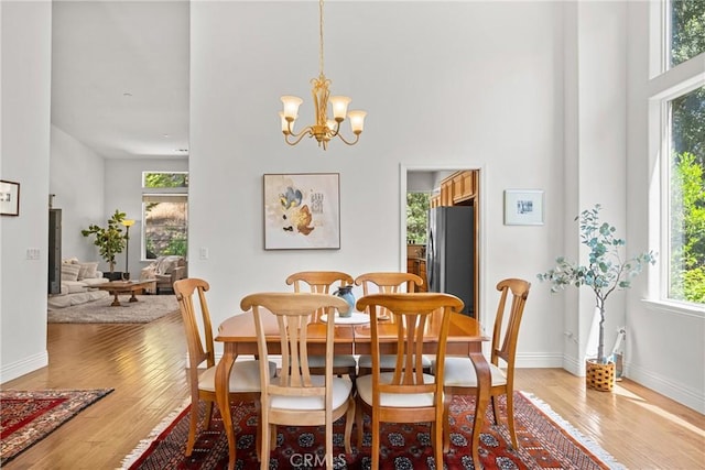 12703 Paso Verde Ct, Atascadero, CA 93422 - dining room featuring light wood-style flooring, a towering ceiling, and a chandelier