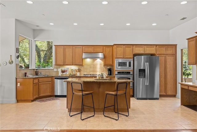 12703 Paso Verde Ct, Atascadero, CA 93422 - kitchen featuring appliances with stainless steel finishes, stone countertops, a kitchen island, tasteful backsplash, and light tile patterned floors
