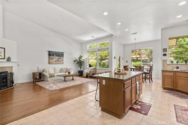 12703 Paso Verde Ct, Atascadero, CA 93422 - kitchen featuring brown cabinetry, open floor plan, recessed lighting, a breakfast bar, and light tile patterned floors