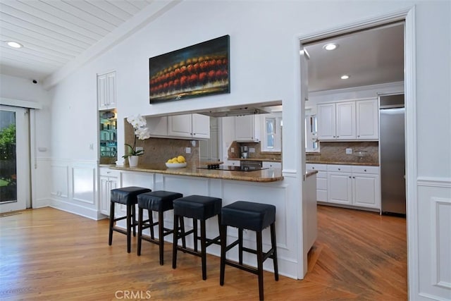 4161 Dixie Canyon Ave, Sherman Oaks, CA 91423 - kitchen with white cabinets, lofted ceiling, a breakfast bar, recessed lighting, and a wainscoted wall