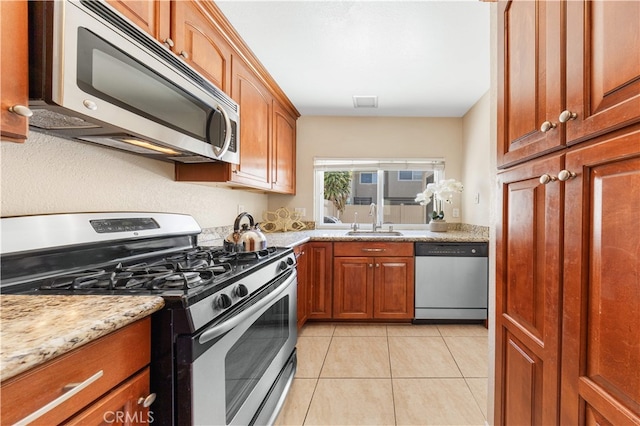 54 Kazan St Unit 27, Irvine, CA 92604 - kitchen featuring appliances with stainless steel finishes, brown cabinets, light tile patterned flooring, and light stone countertops
