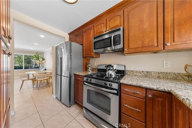 54 Kazan St Unit 27, Irvine, CA 92604 - kitchen featuring stainless steel appliances, light tile patterned floors, brown cabinetry, light stone countertops, and recessed lighting