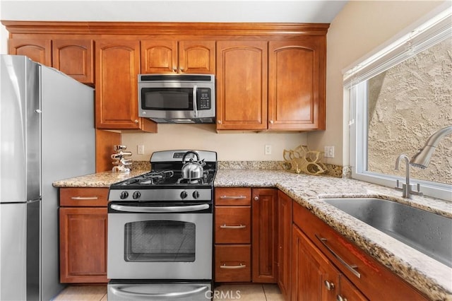 54 Kazan St Unit 27, Irvine, CA 92604 - kitchen with stainless steel appliances, light stone countertops, light tile patterned floors, and brown cabinets