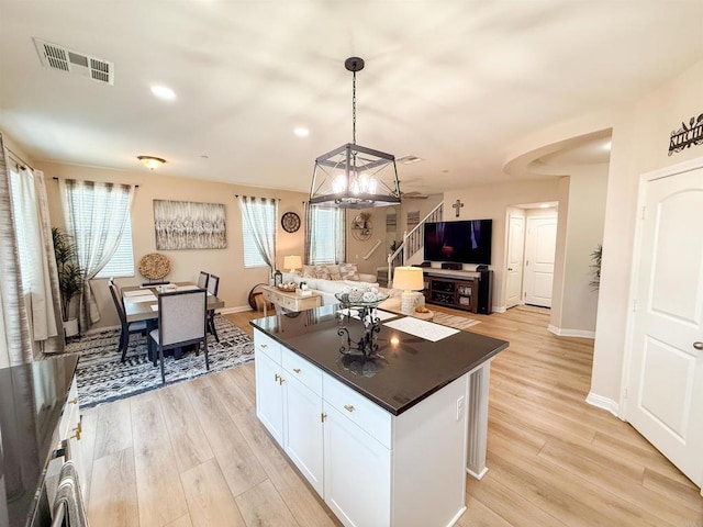 1410 Franceschi Dr, Chula Vista, CA 91913 - kitchen with dark countertops, open floor plan, light wood-style flooring, a center island, and white cabinets