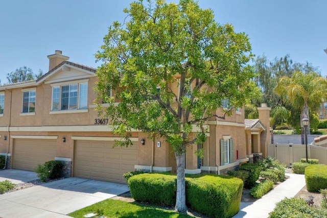33657 Emerson Way Unit C, Temecula, CA 92592 - view of property featuring stucco siding, concrete driveway, a garage, and a chimney