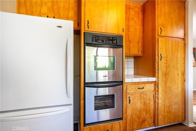46404 Kings Canyon Rd, Lancaster, CA 93536 - kitchen with freestanding refrigerator, double oven, tile countertops, and brown cabinets