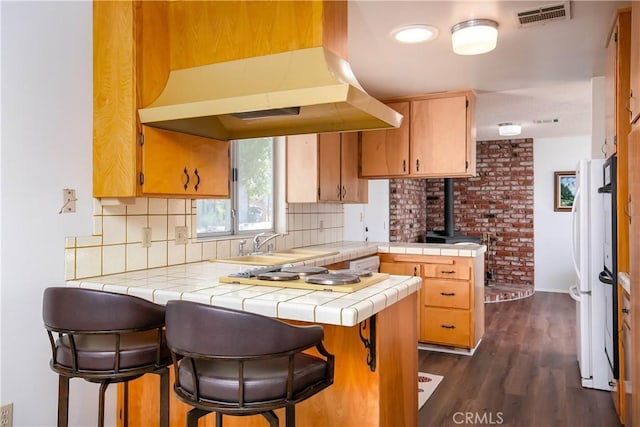 46404 Kings Canyon Rd, Lancaster, CA 93536 - kitchen featuring a peninsula, tile counters, exhaust hood, backsplash, and a wood stove