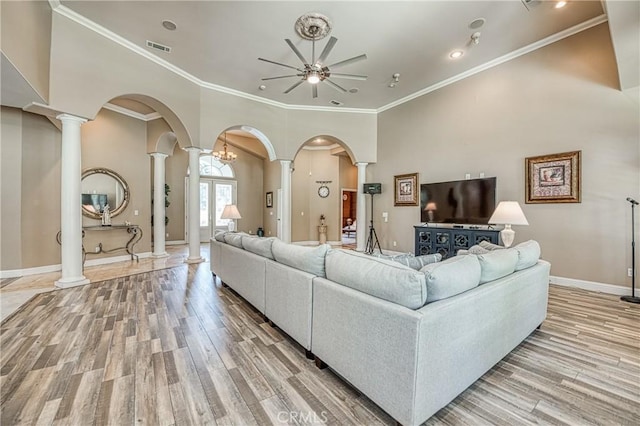 2457 Remington Ct, Merced, CA 95340 - living room featuring decorative columns, arched walkways, ceiling fan, light wood finished floors, and crown molding