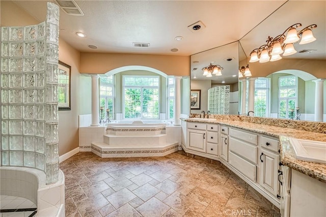 2457 Remington Ct, Merced, CA 95340 - bathroom with decorative columns, double vanity, a bath, and stone tile floors