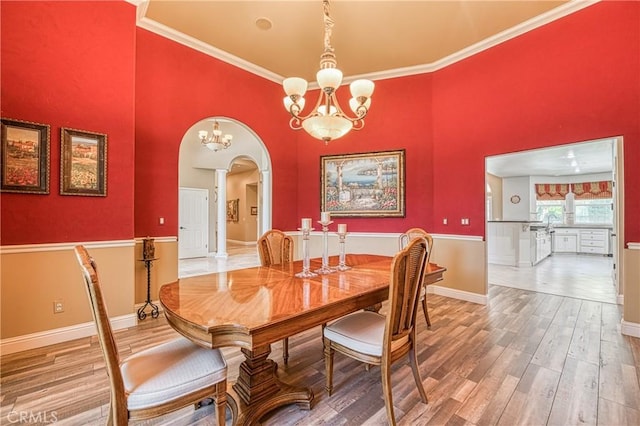 2457 Remington Ct, Merced, CA 95340 - dining room with arched walkways, a chandelier, wood finished floors, decorative columns, and ornamental molding