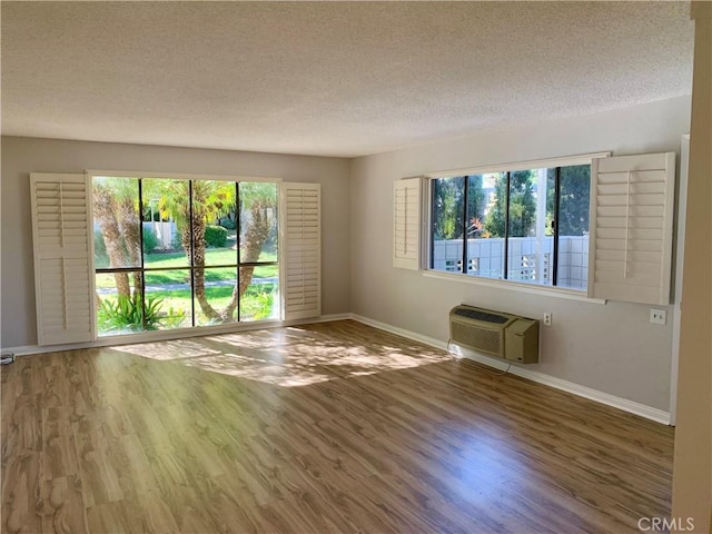 930 Avenida Majorca Unit A, Laguna Woods, CA 92637 - unfurnished room with wood finished floors, plenty of natural light, a textured ceiling, and an AC wall unit