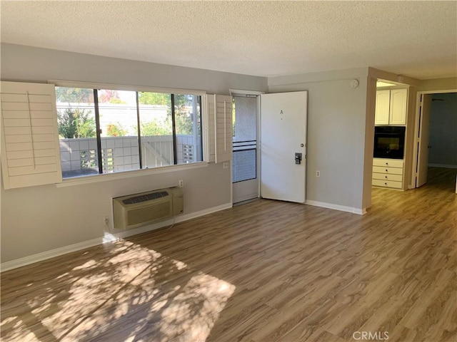930 Avenida Majorca Unit A, Laguna Woods, CA 92637 - unfurnished living room with a textured ceiling, wood finished floors, and an AC wall unit