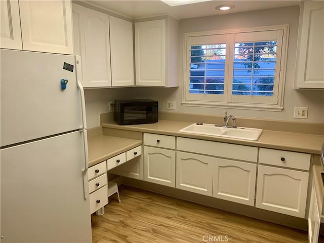 930 Avenida Majorca Unit A, Laguna Woods, CA 92637 - kitchen featuring freestanding refrigerator, black microwave, white cabinetry, light wood-style flooring, and light countertops