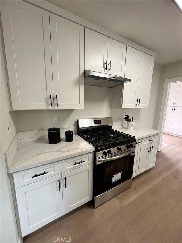 13723 Pinney St, Pacoima, CA 91331 - kitchen featuring stainless steel gas range oven, under cabinet range hood, light wood-style flooring, and white cabinetry